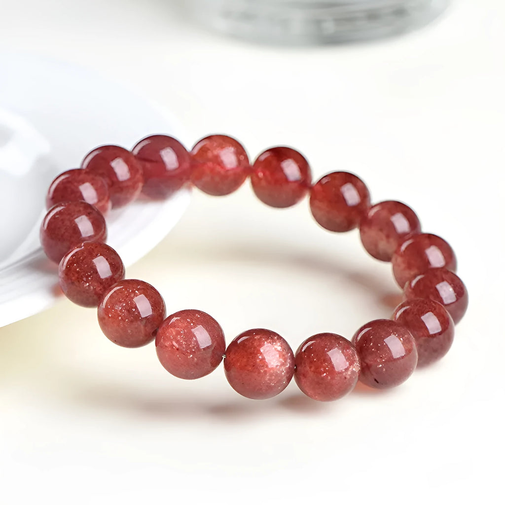 Natural red strawberry quartz crystal bracelet with geometric beads showing a starlight effect, laid flat.