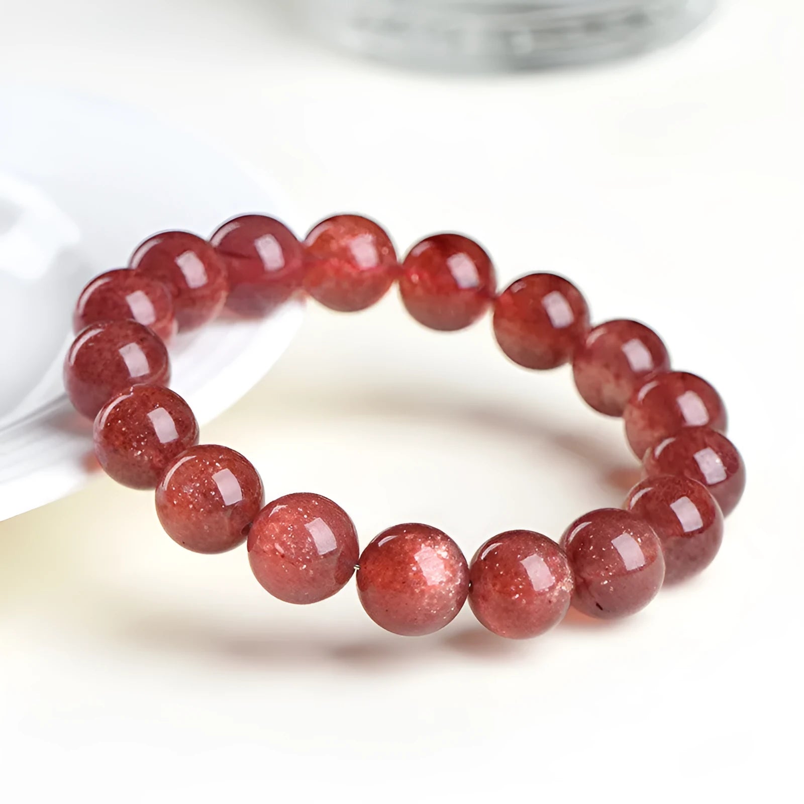 Natural red strawberry quartz crystal bracelet with geometric beads showing a starlight effect, laid flat.