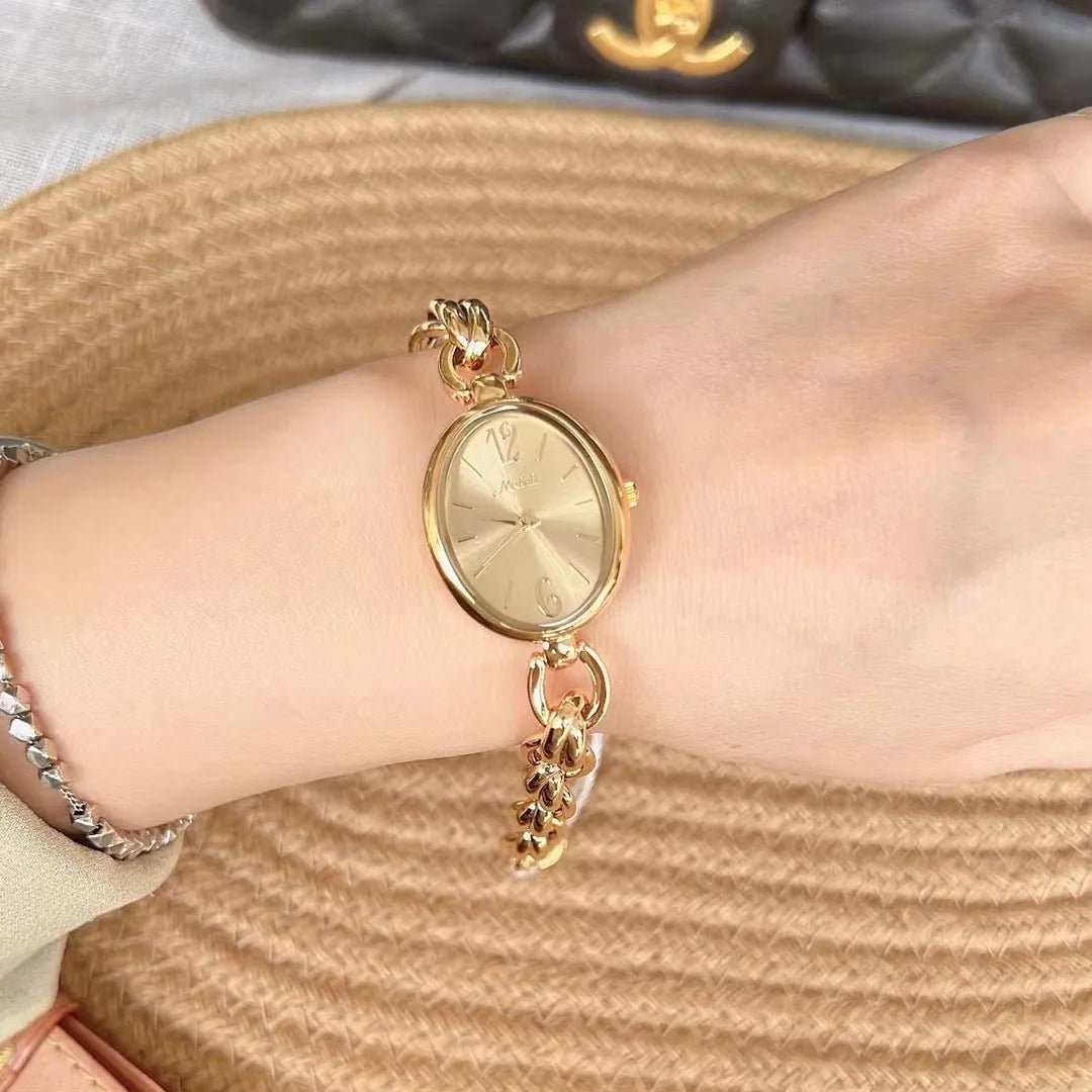 Lady's steel strap quartz watch with oval hollow chain in gold case gold face design