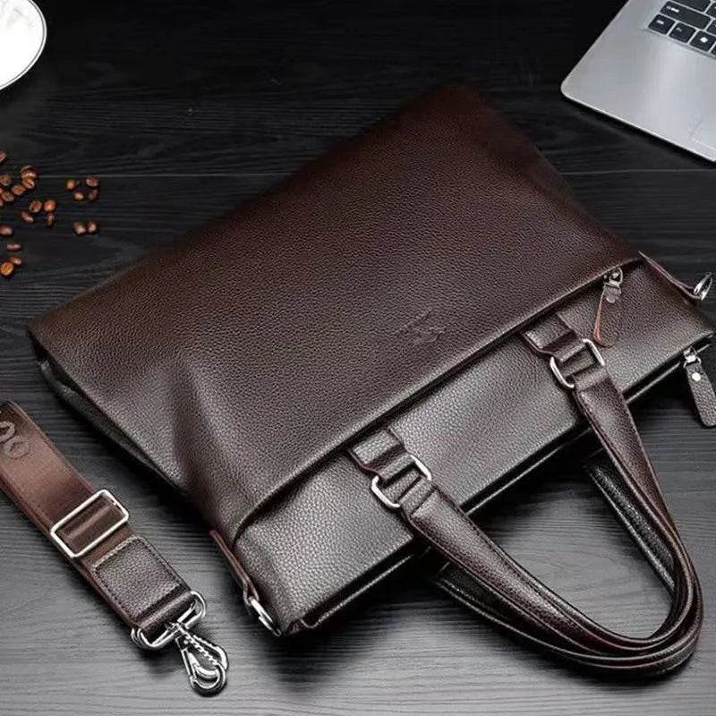 Men's black PU leather crossbody messenger bag with splicing design, shown next to a tablet for scale.