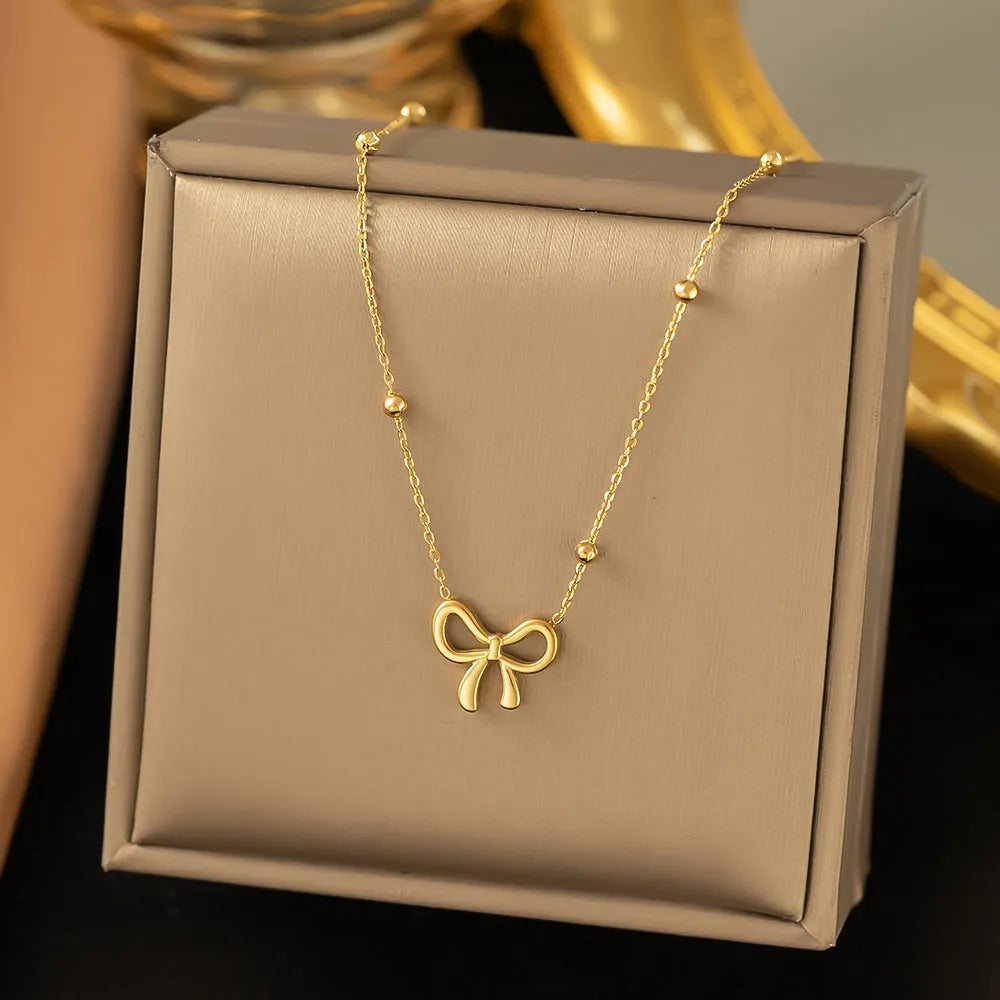 Gold titanium steel bow necklace with cross chain design on display