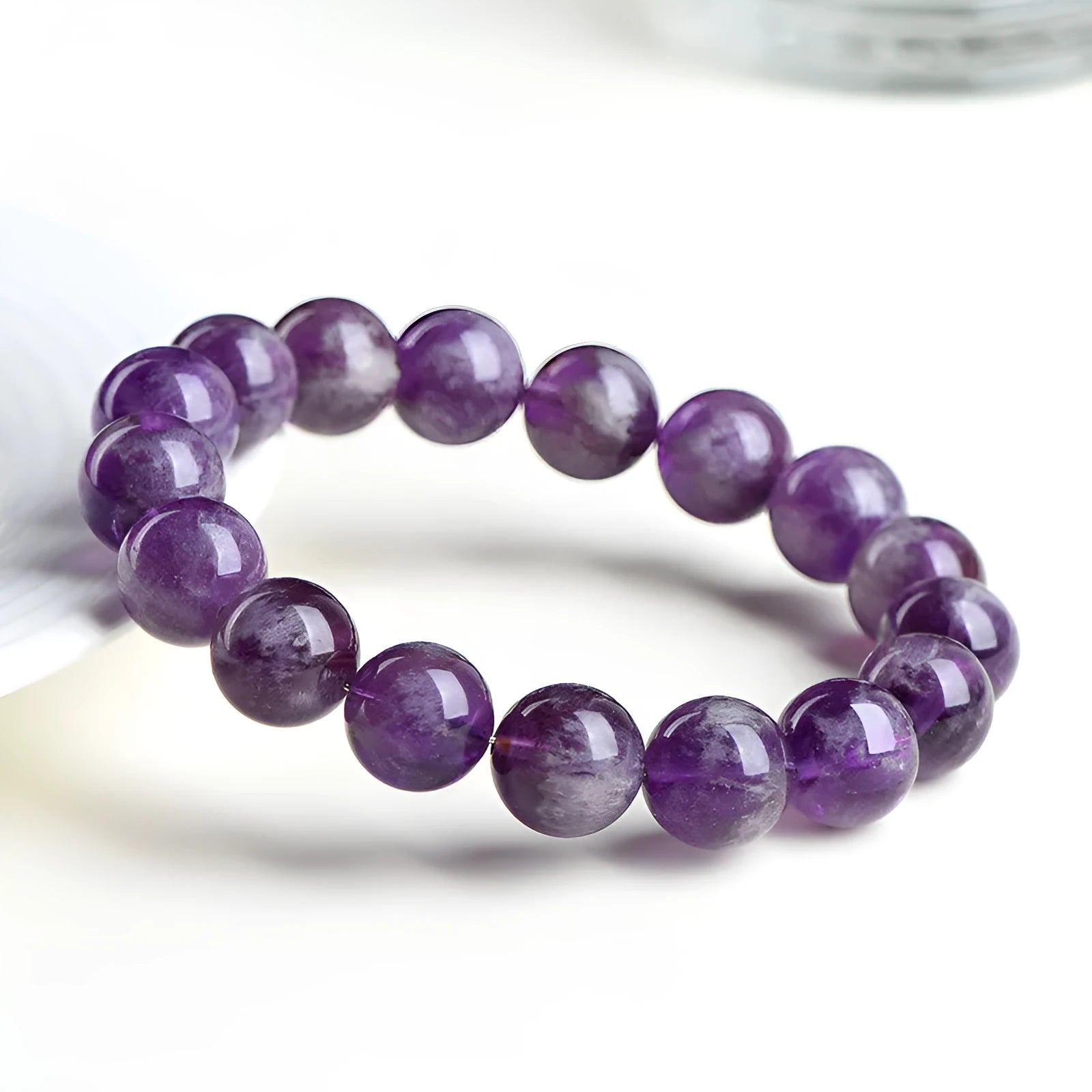 Natural purple feather amethyst crystal bracelet with scattered beads and geometric Ruyi pattern on a wrist.