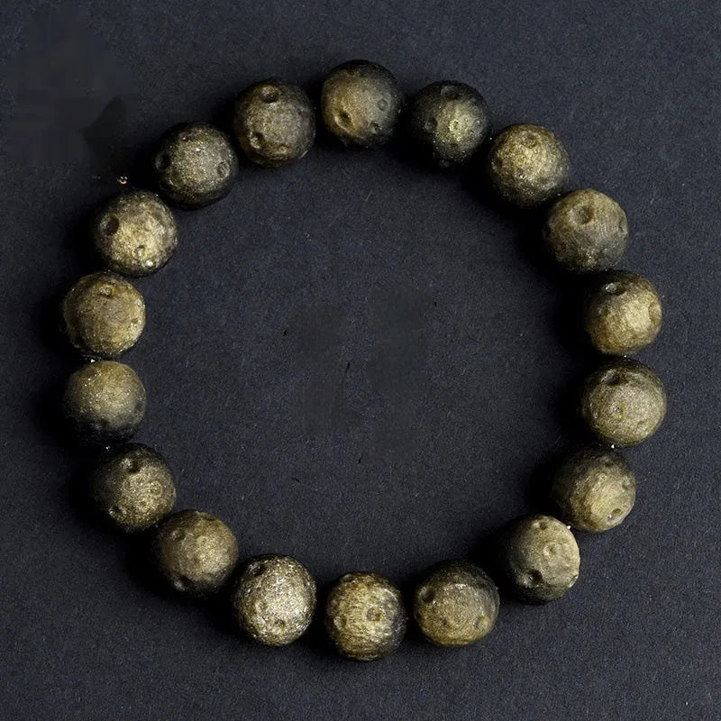 Natural obsidian crater ball bracelet in gold or silver meteorite finish on a wrist.