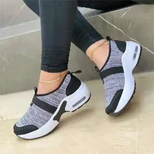 Women's white mesh flat sneakers with round toe and rubber sole on a light background.