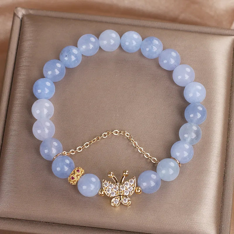 Sky blue crystal butterfly stretch bracelet for women with pearl and rhinestone accents on a plain background