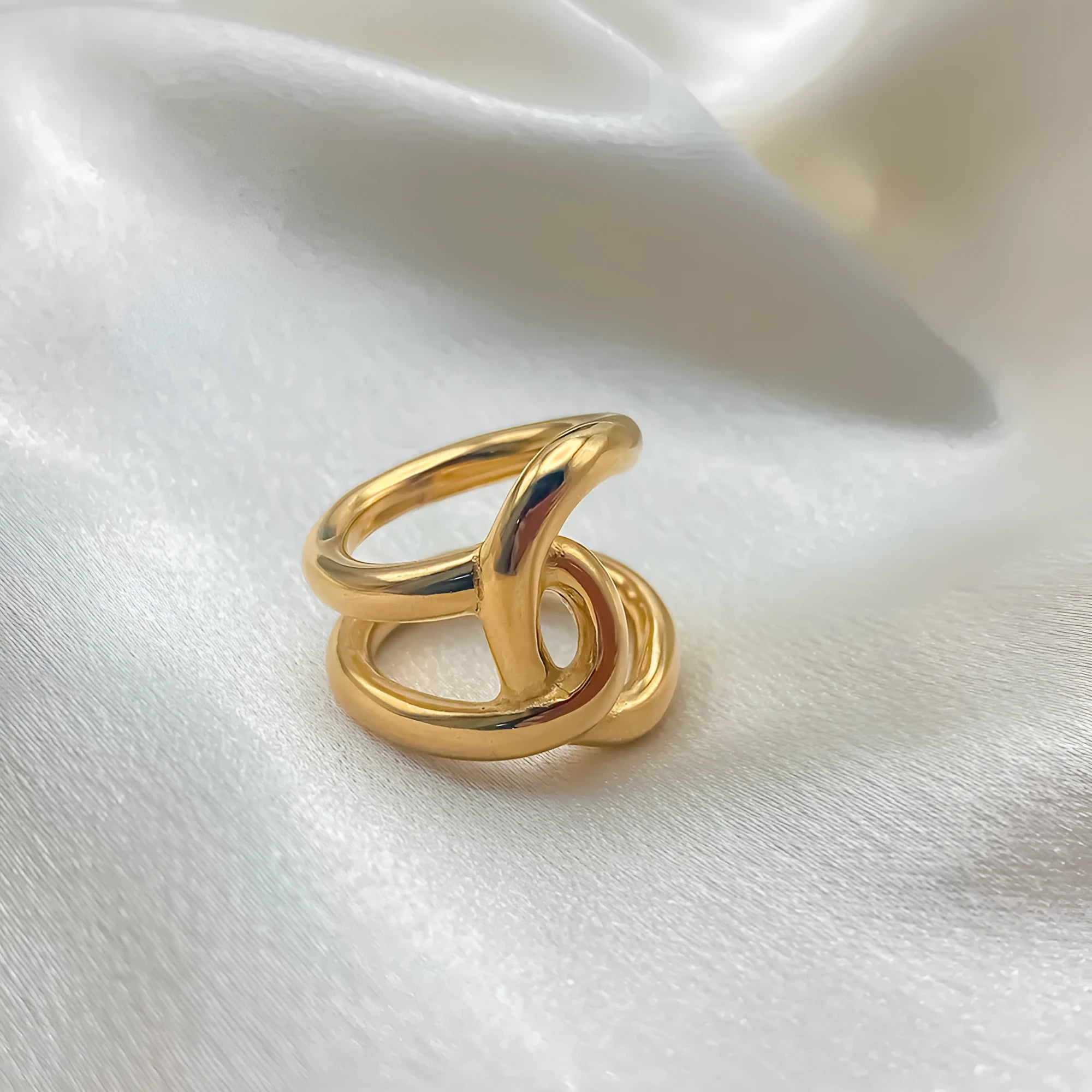 Adjustable knotted stainless steel ring in geometric U-shape, shown in gold and steel colours.