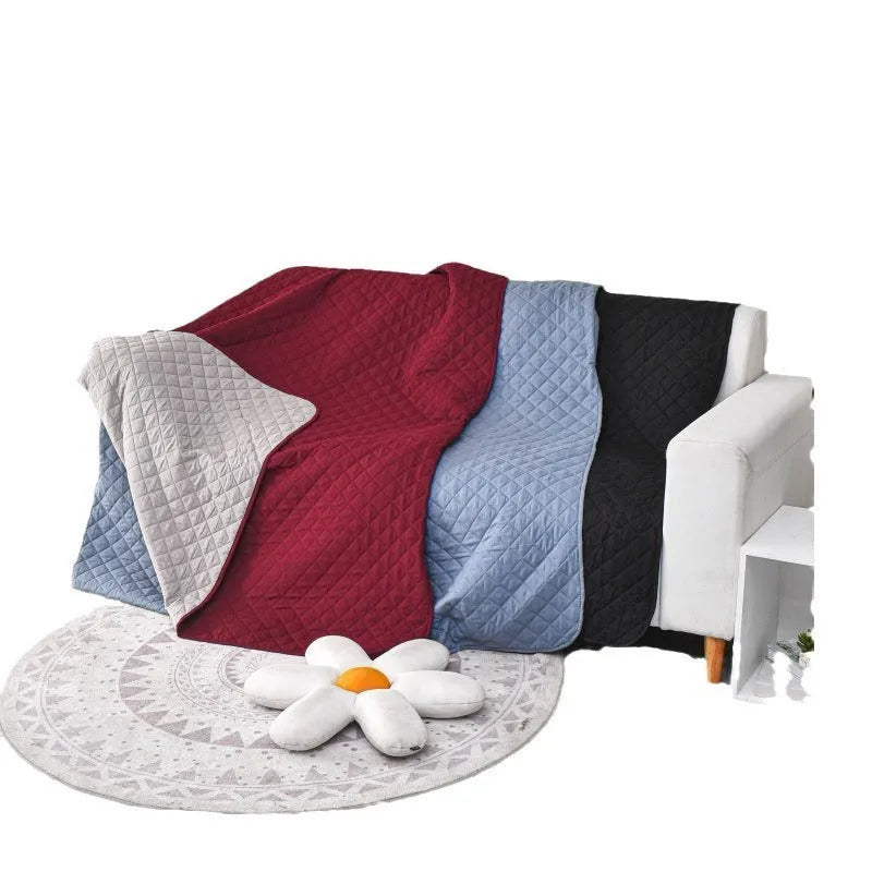 Reversible dog blanket on sofa showing two colour sides, protecting furniture from pets
