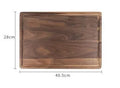 Black walnut wood cutting board with groove edge, rectangular shape, on kitchen counter