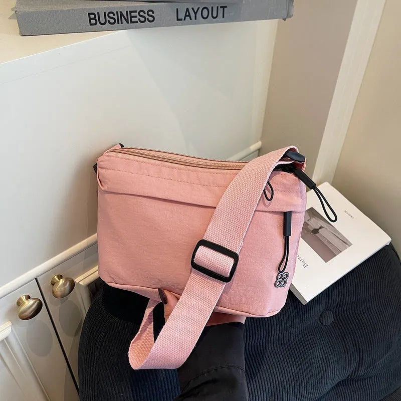 Lightweight cloth crossbody bag in black with horizontal square shape, sandwich pocket, and canvas lining