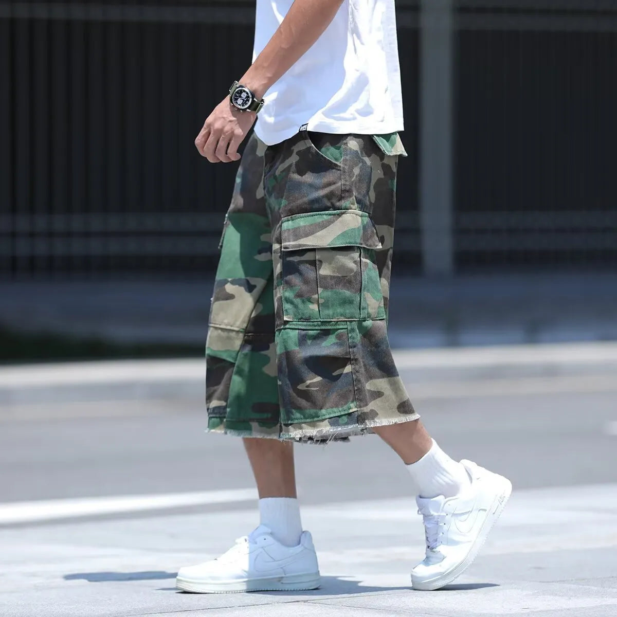 Man wearing loose-fit cropped camouflage shorts in retro American workwear style.