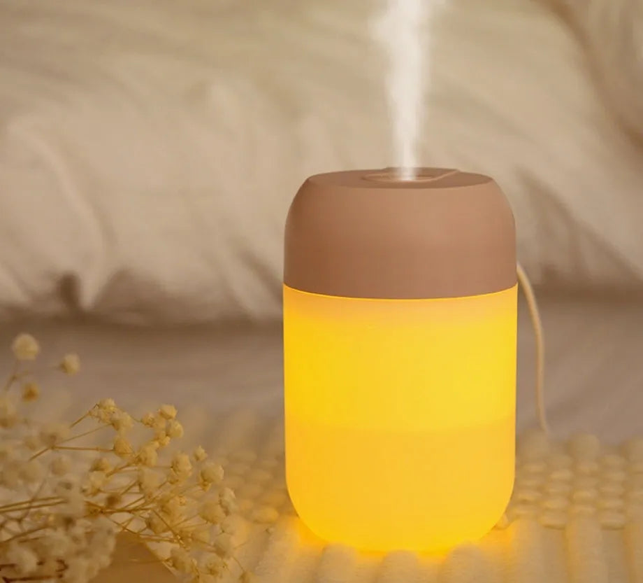 White cylindrical USB mini humidifier with charging cable on desk