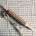 Natural wooden rolling pin with Christmas embossing patterns, 45 cm length, on a light background
