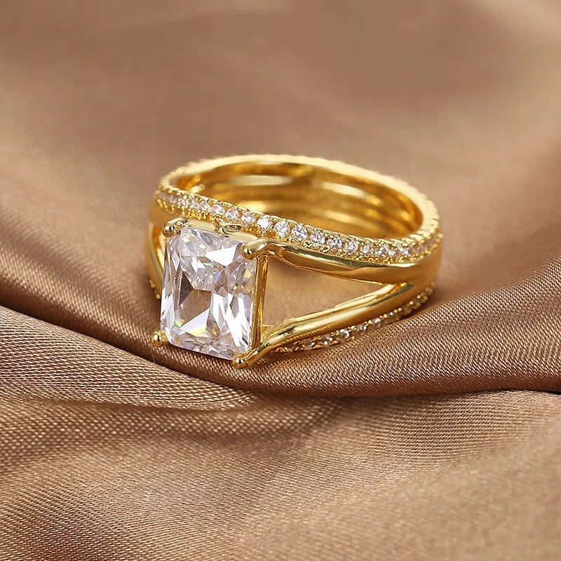 Gold geometric women's ring with a square zircon stone on a hand.