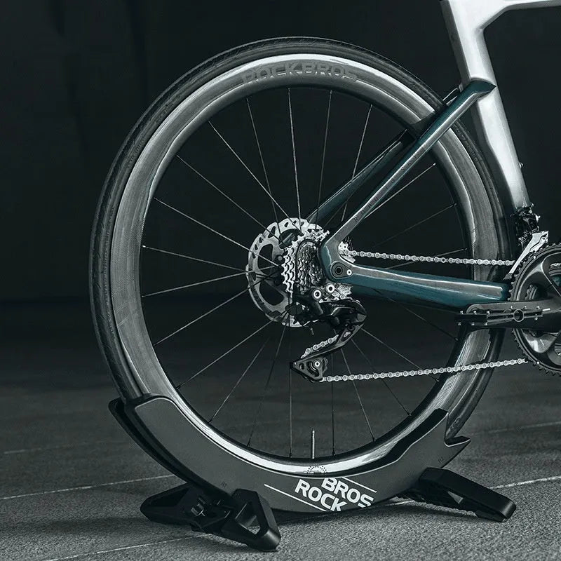 ABS wall-mounted bike parking rack holder in black holding a bicycle frame against a garage wall