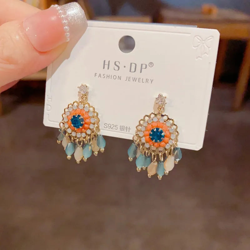 Pair of diamond embedded round crystal tassel earrings, thick gold plated, purple colour, on a white background