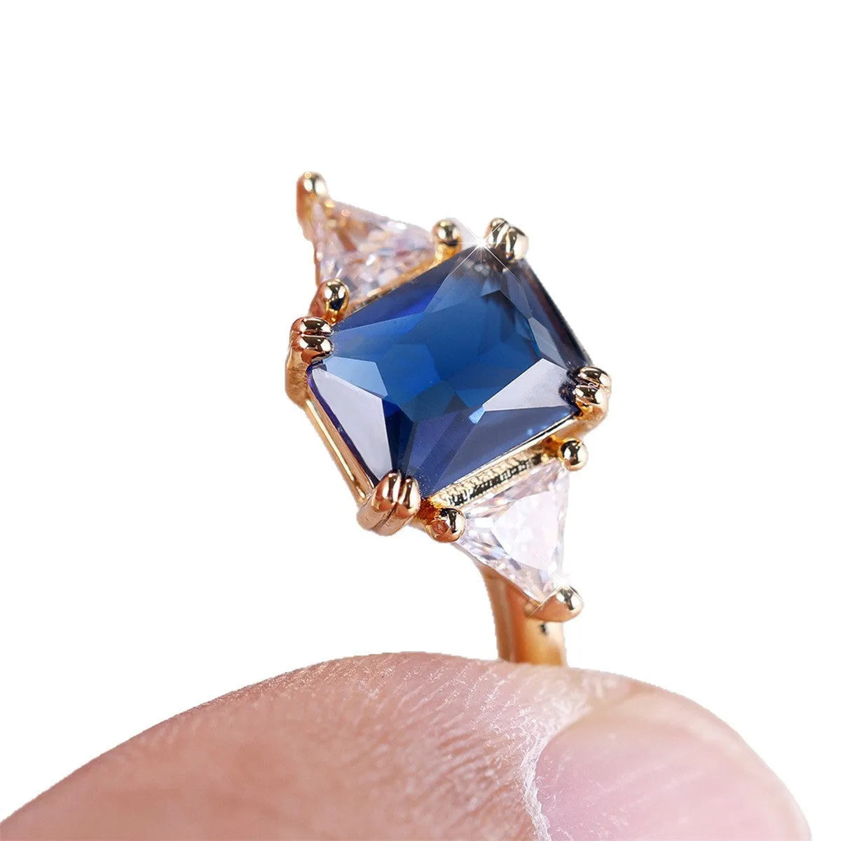 Gold sapphire blue rectangular copper ring for women on plain background