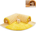 Brown plaid plush cat tunnel bed with a central mat on a wooden floor.