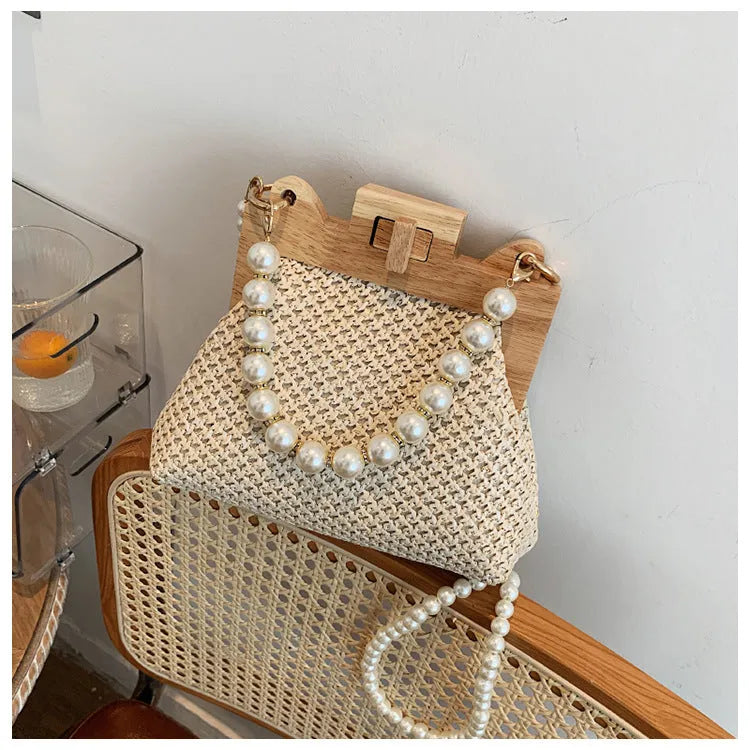 Women's woven straw shoulder bag with pearl chain detailing and multiple interior compartments