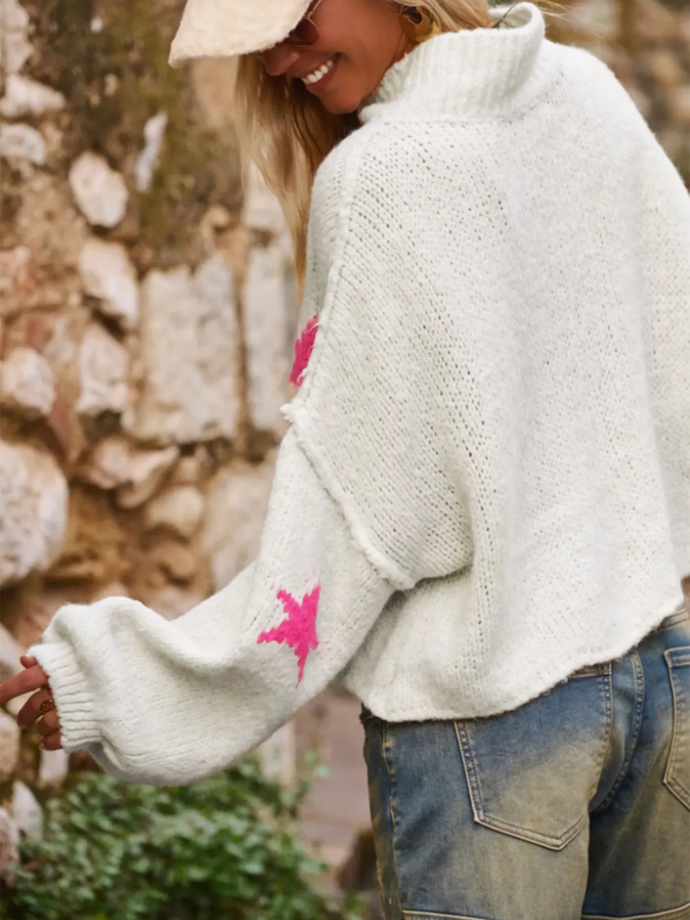 White women's turtleneck pullover sweater with a black five-pointed star pattern on the front.