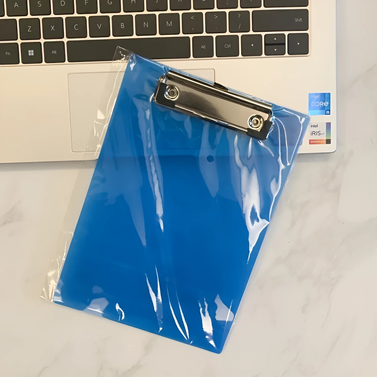 Transparent plastic A4 plate holder with metal clip and integrated writing board surface, shown in blue.