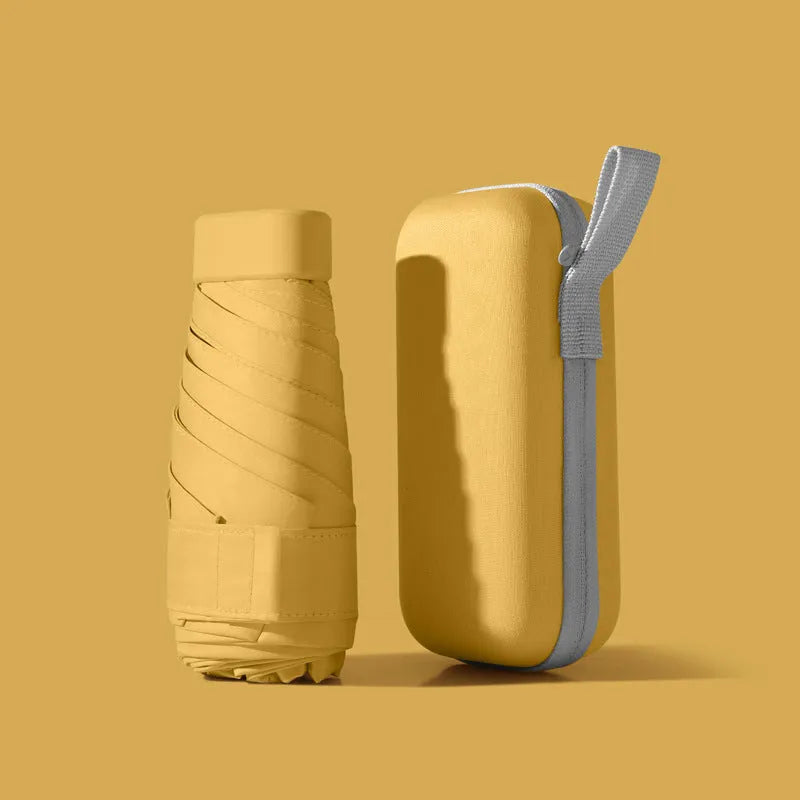Compact six-fold umbrella in mint green with a capsule box, showing its folded size and rubber handle.