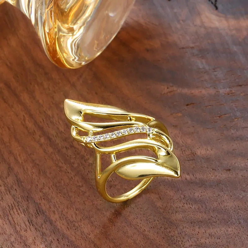 Gold tone exaggerated curve copper ring with zircon stone on white background