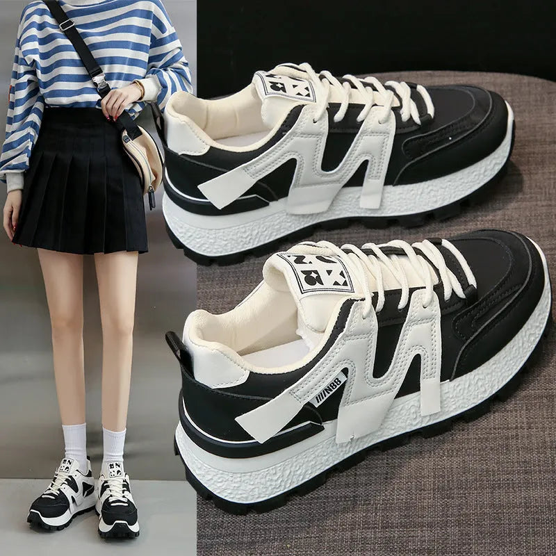 Low-top white and black casual sneakers with round toe and lace-up closure on a plain background.