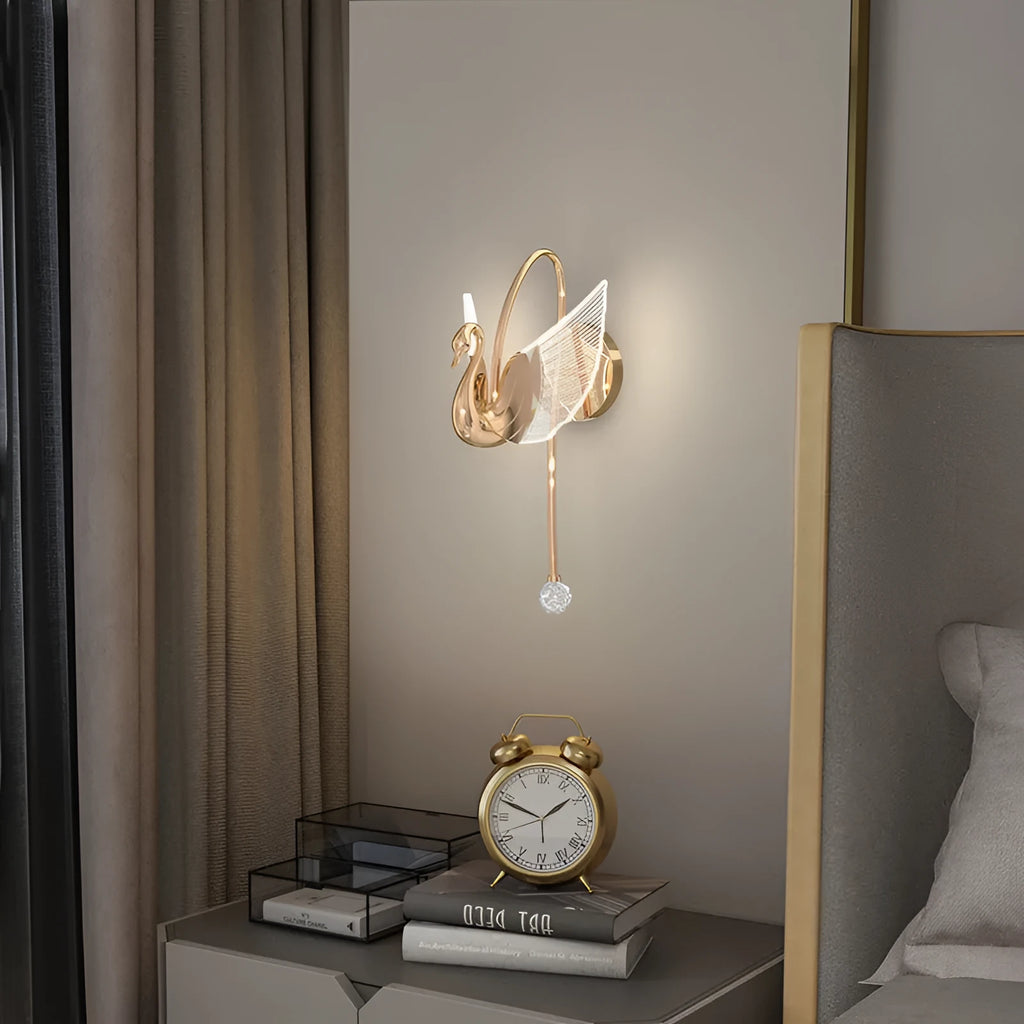 Modern gold swan-shaped wall lamp with acrylic shade mounted beside bed