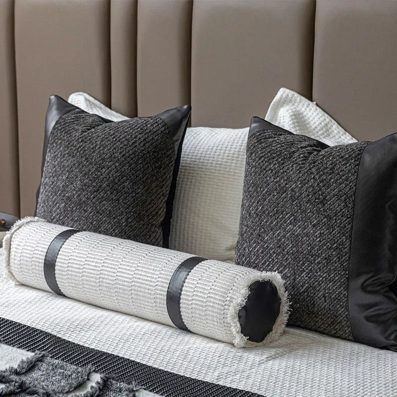 Grey and white plaid bed runner blanket with leather round pillow on bed