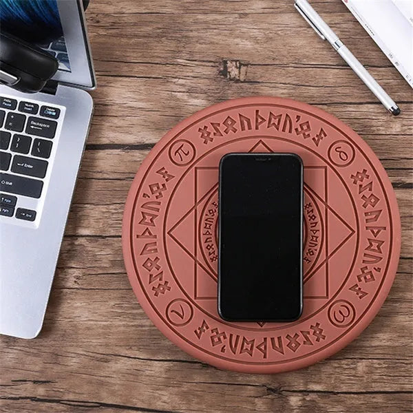 Square black wireless charging pad with illuminated magic array pattern, shown with a smartphone on top.