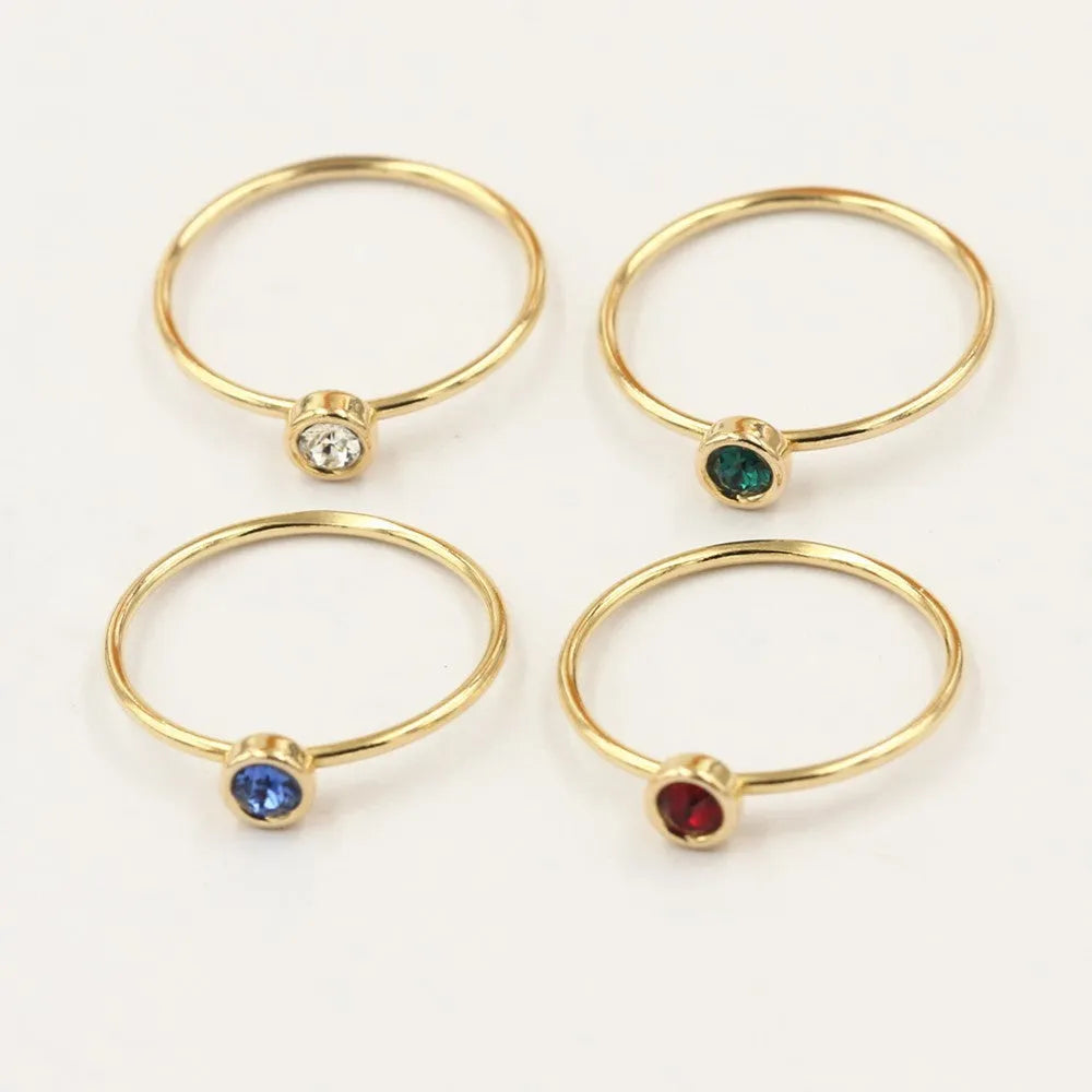 Gold-plated women's knuckle ring with clear stones in green, blue, red, or white on a copper band.