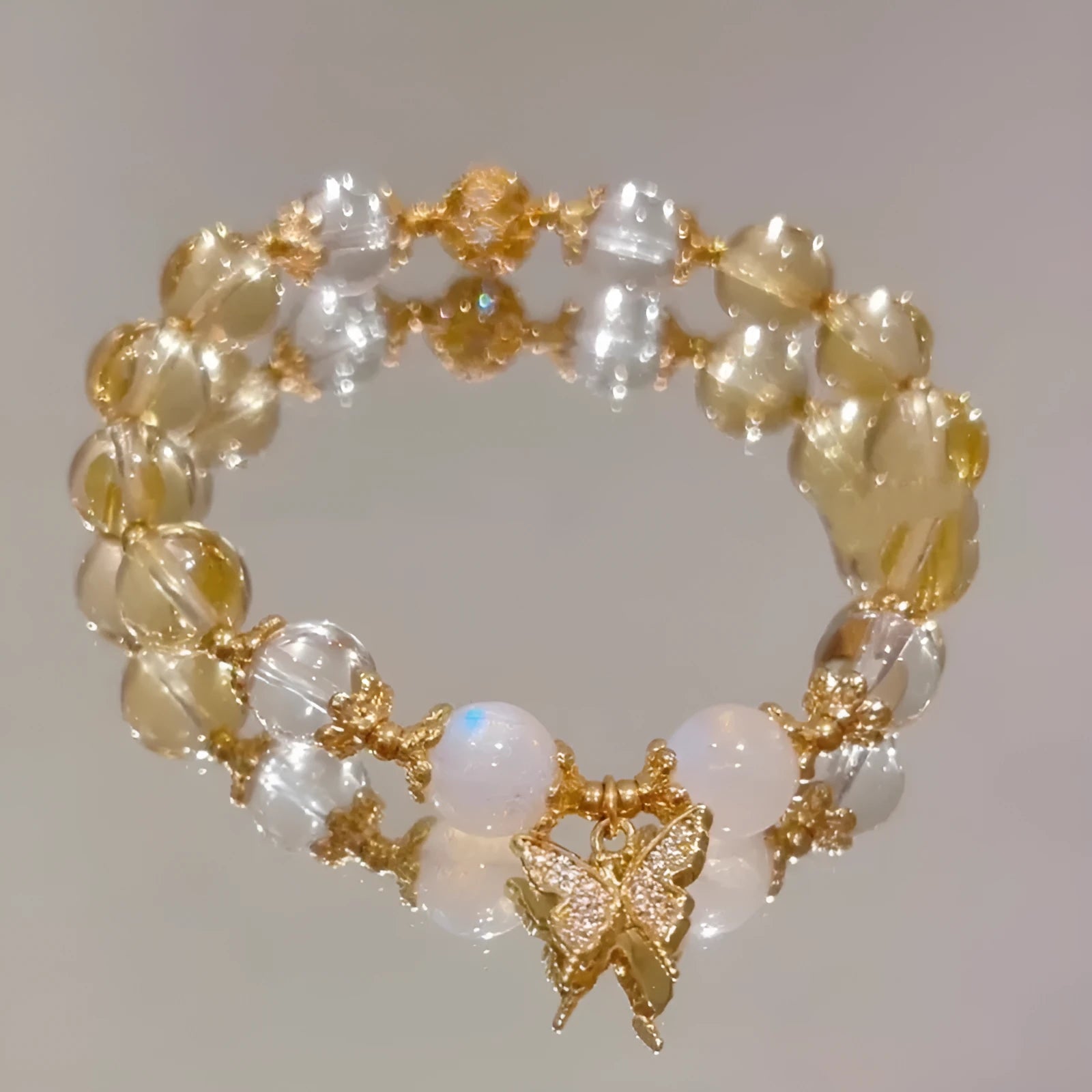 Moonstone white crystal beaded bracelet with citrine butterfly pendant on a white background