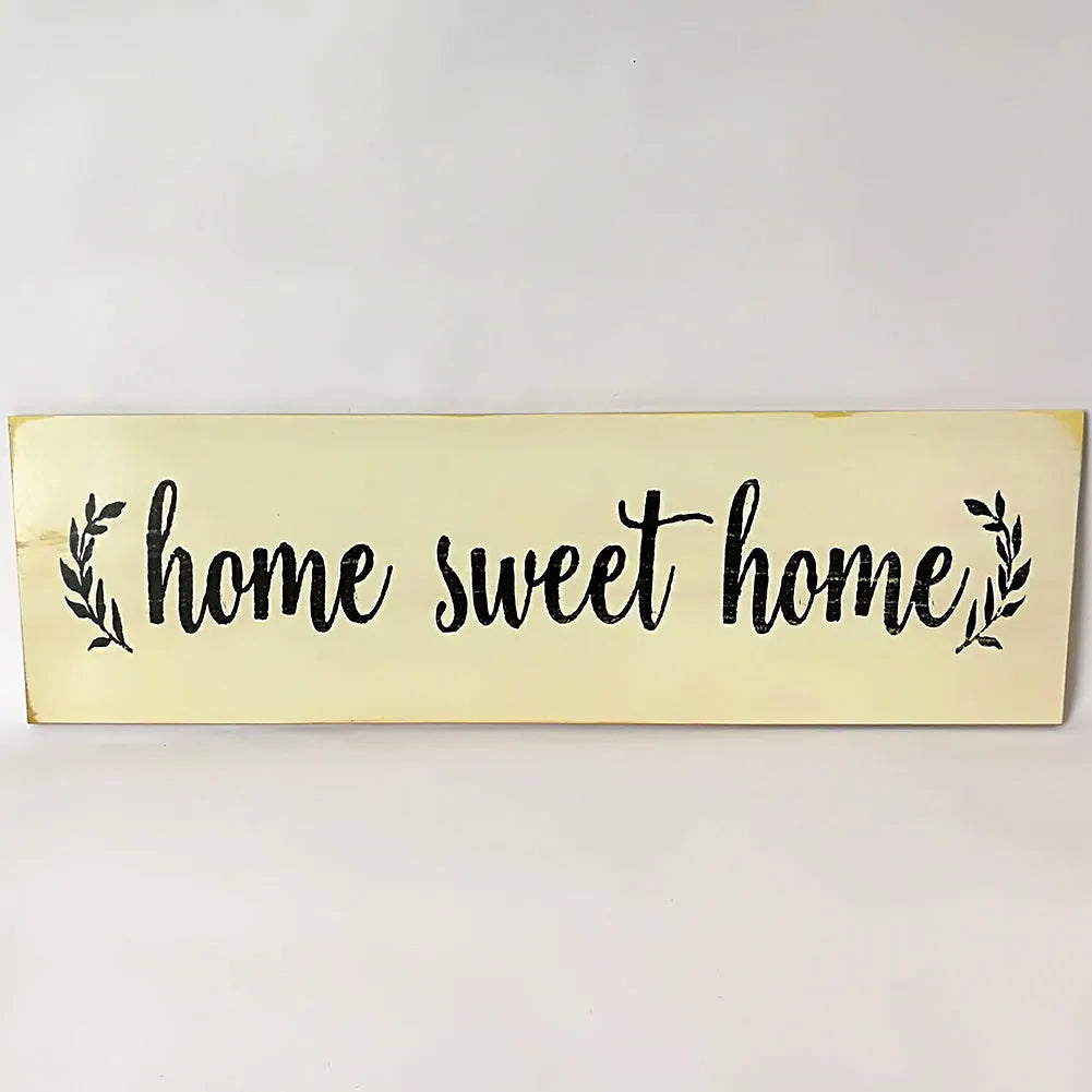 Home Sweet Home wooden carved pendant in black, 40cm x 12cm, hanging on a light wall