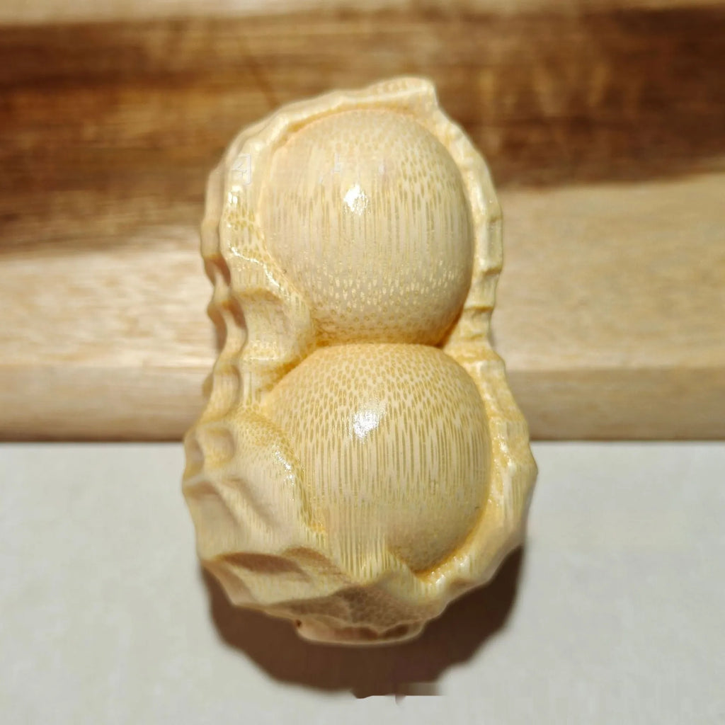 Solid natural bamboo ornament carved into a peanut shape on a wooden surface.