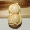 Solid natural bamboo ornament carved into a peanut shape on a wooden surface.