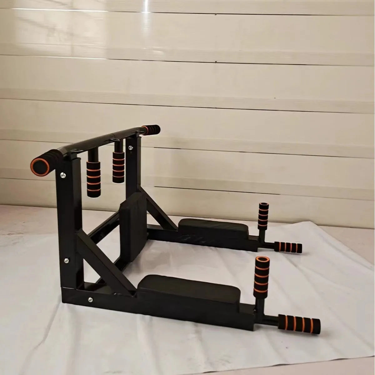 Black wall-mounted metal fitness rack with sandbag holder, parallel bars, and pull-up station.