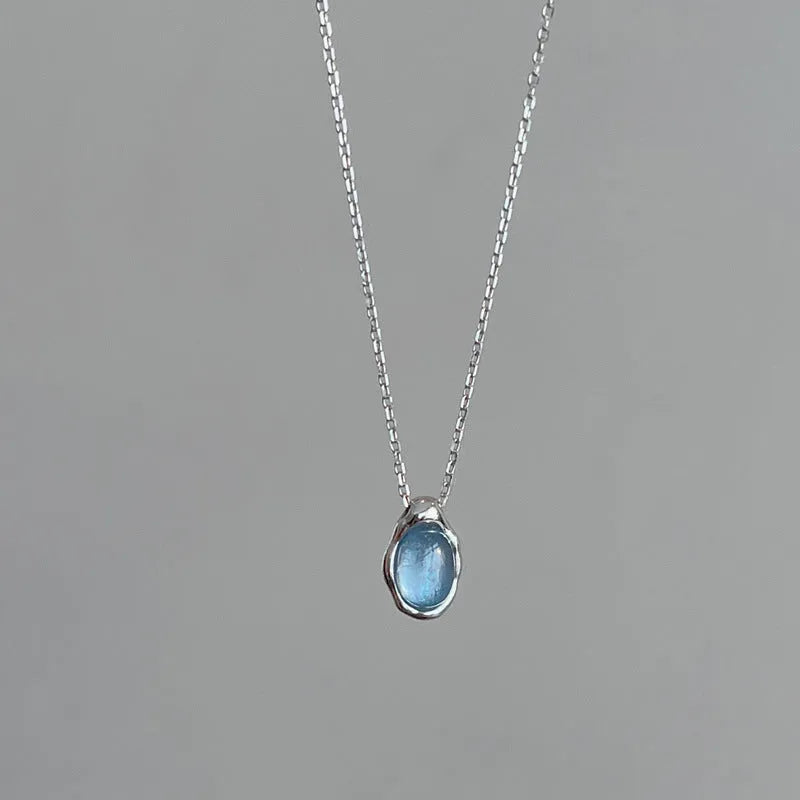 Navy blue water droplet necklace with geometric cross chain on white background