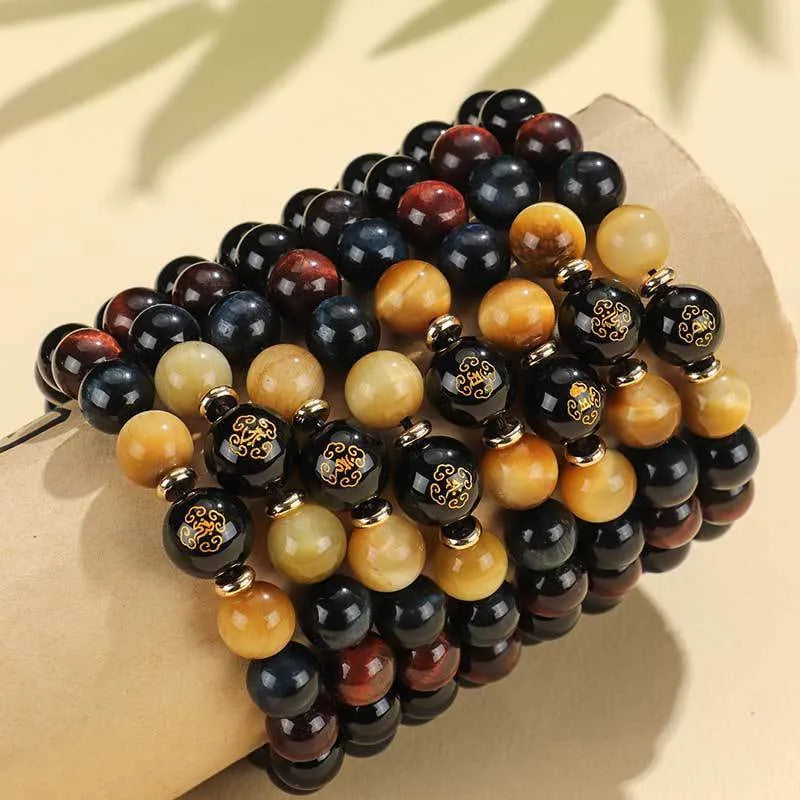 Black agate beaded bracelet with gold tiger eye accent and Chinese zodiac bodhisattva charm on neutral background
