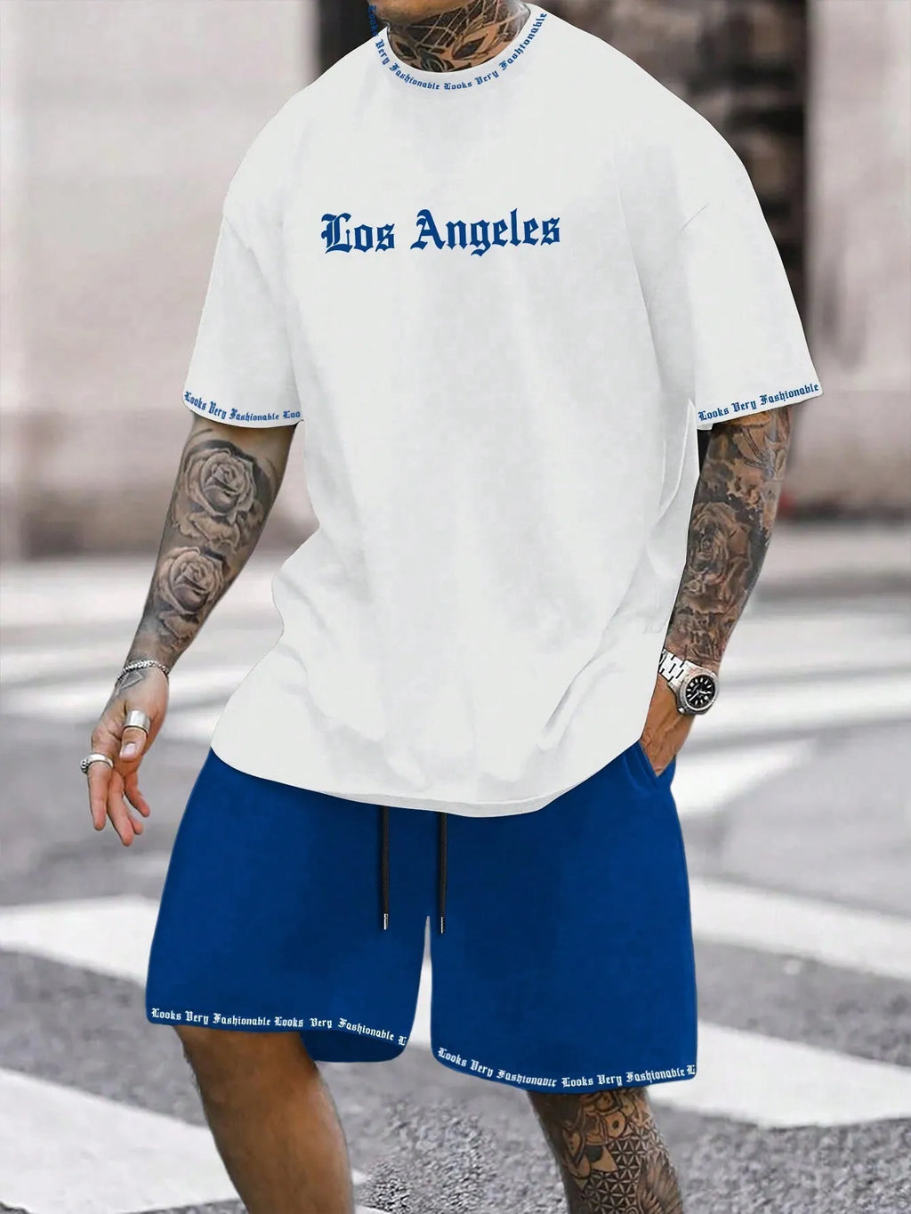 Man wearing a blue printed short-sleeved top and matching shorts from a sports-style two-piece set.
