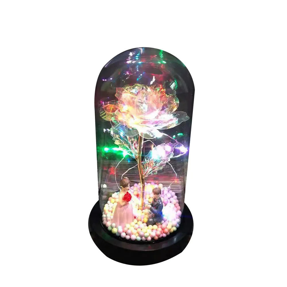 Gold artificial rose inside glass dome with LED lights on black base for home display