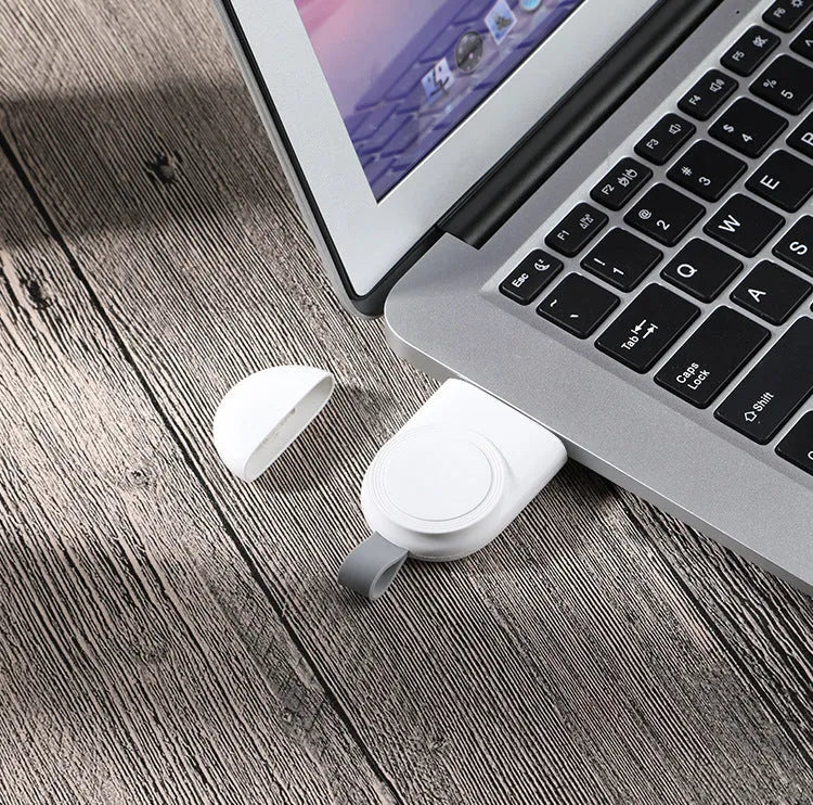 Portable wireless Apple Watch charging dock in white on a desk, with USB cable attached