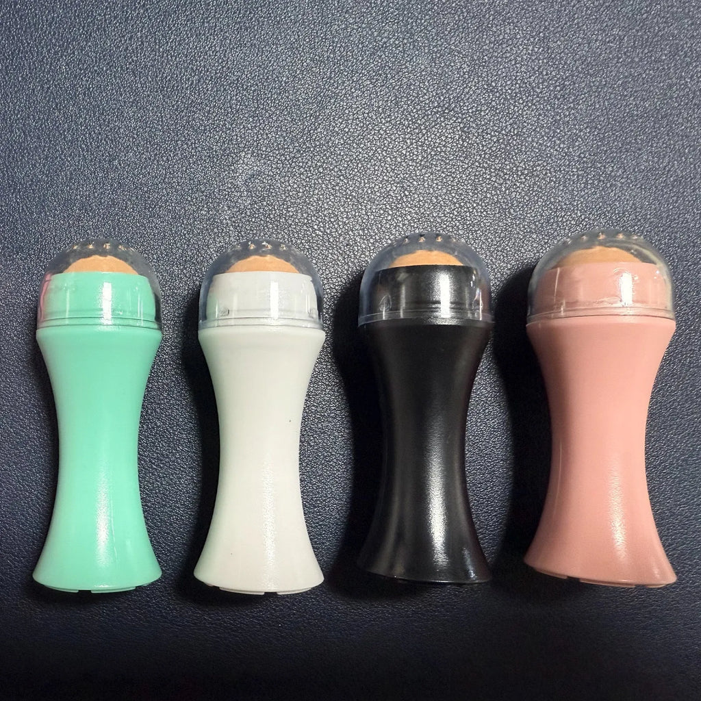 Volcanic stone facial roller for oily skin in black, green, pink, or white on a plain background