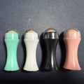 Volcanic stone facial roller for oily skin in black, green, pink, or white on a plain background