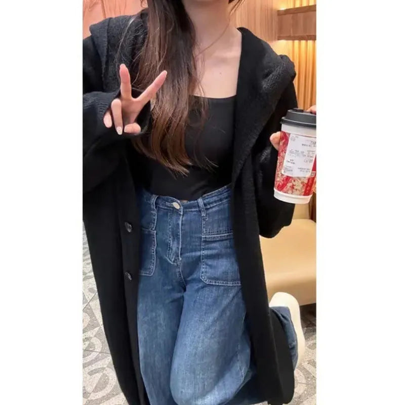Woman wearing a long, loose, hooded knitted cardigan in a neutral colour, Korean casual style.