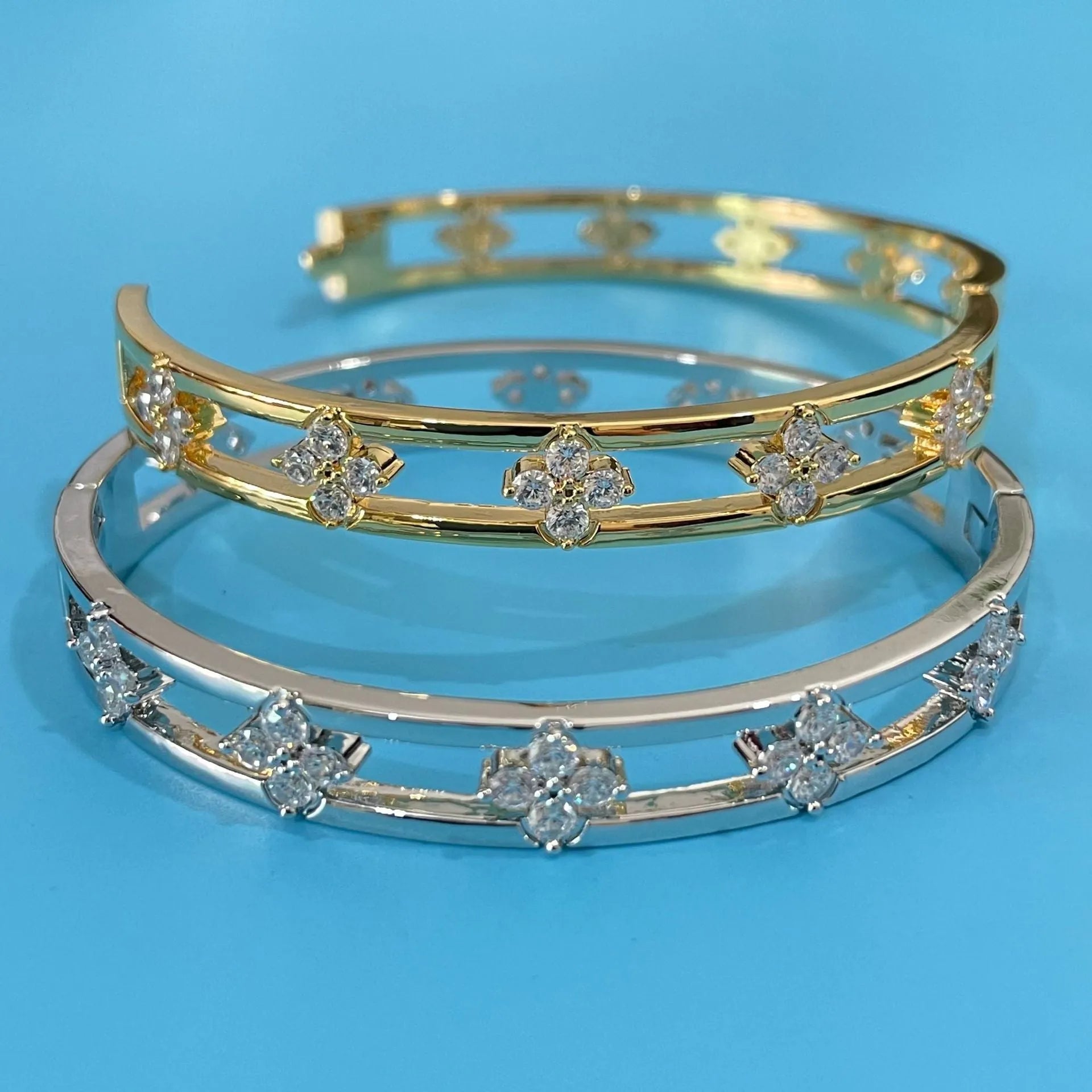 Gold and silver women's hollow bracelet with zircon inlay and a four-leaf clover design.