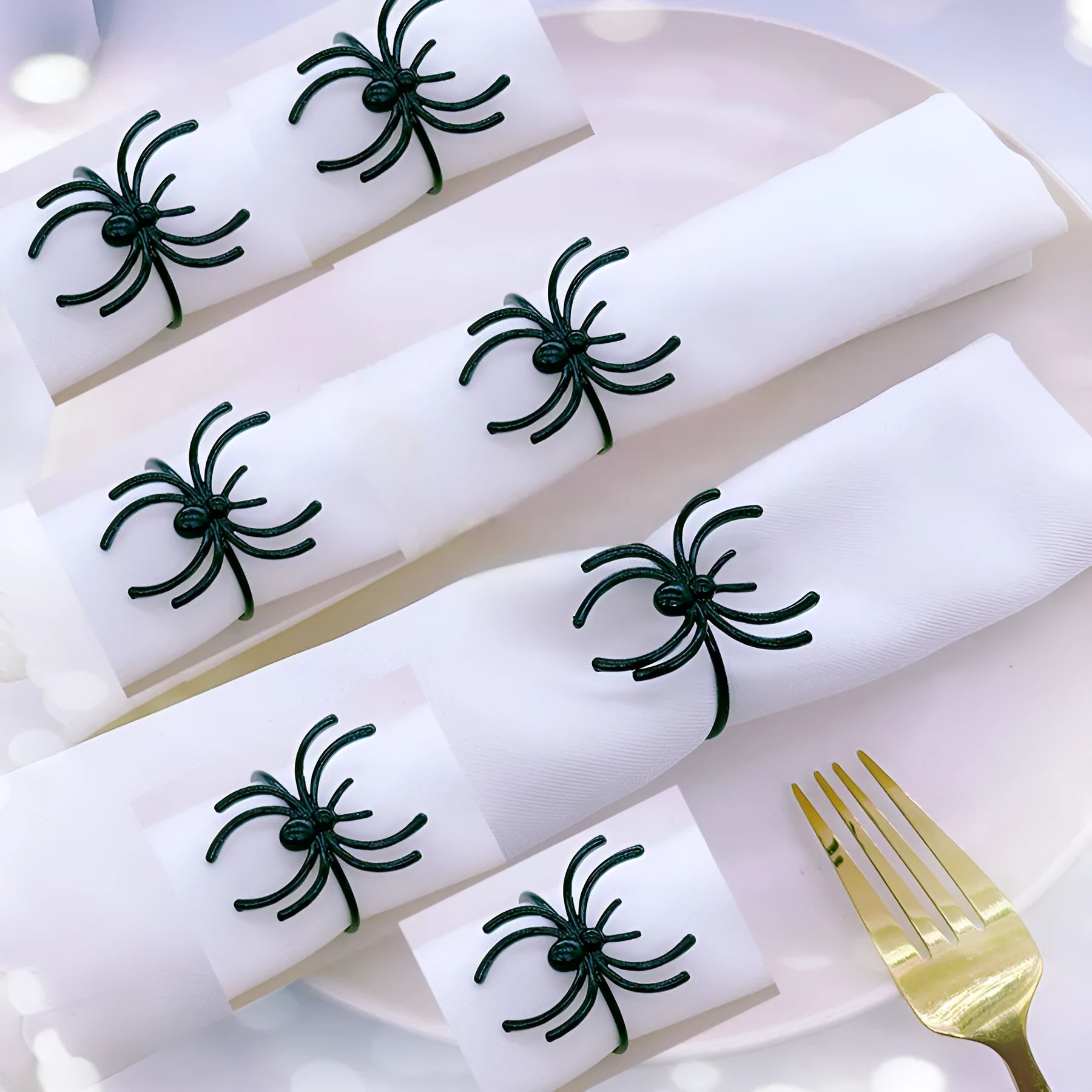 Six black alloy spider-shaped napkin rings for Halloween table decoration on a dark surface.