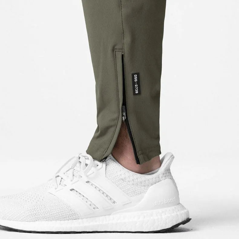 Men's grey quick-dry fitness trousers with ankle-tied design on exercise equipment