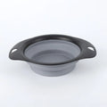 Silicone folding bowl for pets in black and green, collapsed flat for storage, portable outdoor cat and dog food bowl