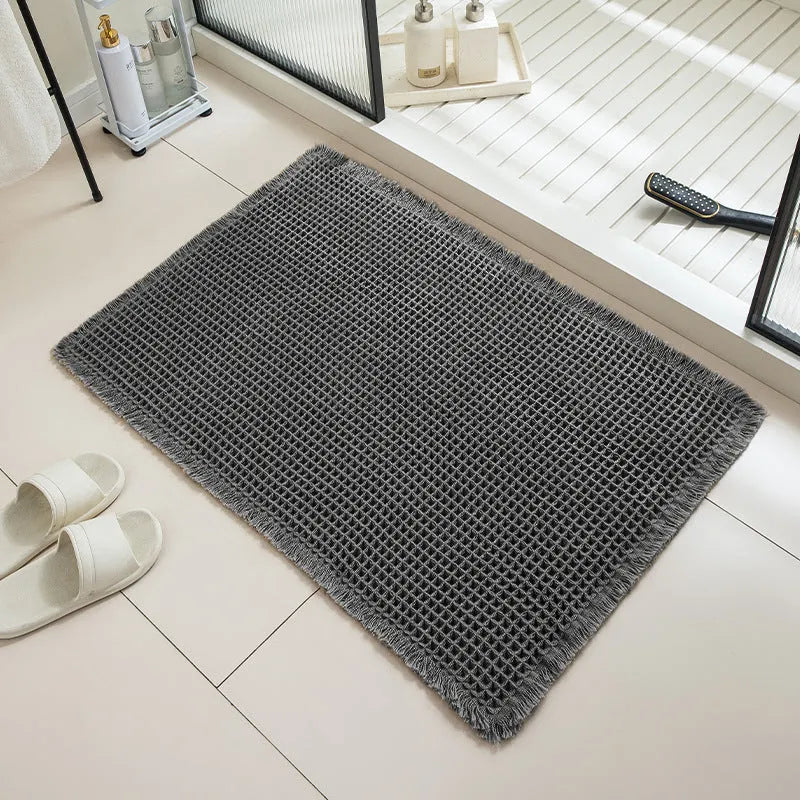 Square checkered pattern bathroom mat on tiled floor in a neutral beige colour.
