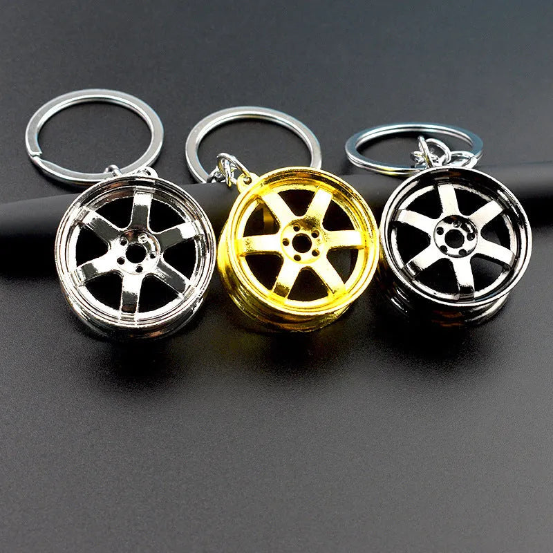Zinc alloy car wheel hub keychain in gold finish with detailed hub pattern on white background